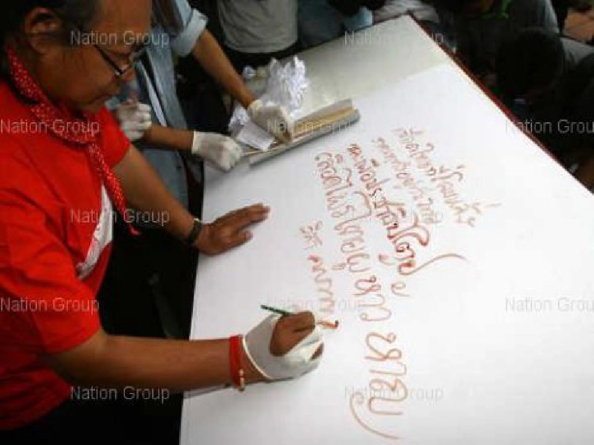 ศิลปินเสื้อแดงนำเลือดเขียนป้ายกดดันรบ.  