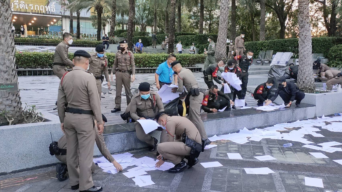 เจ้าหน้าที่ตำรวจช่วยกันเก็บแผ่นกระดาษที่กลุ่มมวลชนโปรยทิ้งไว้หลังแสดงความไม่พอใจคำวินิจฉัยศาลรัฐธรรมนูญ ชี้ขบวนการล้มล้างการปกครองฯ